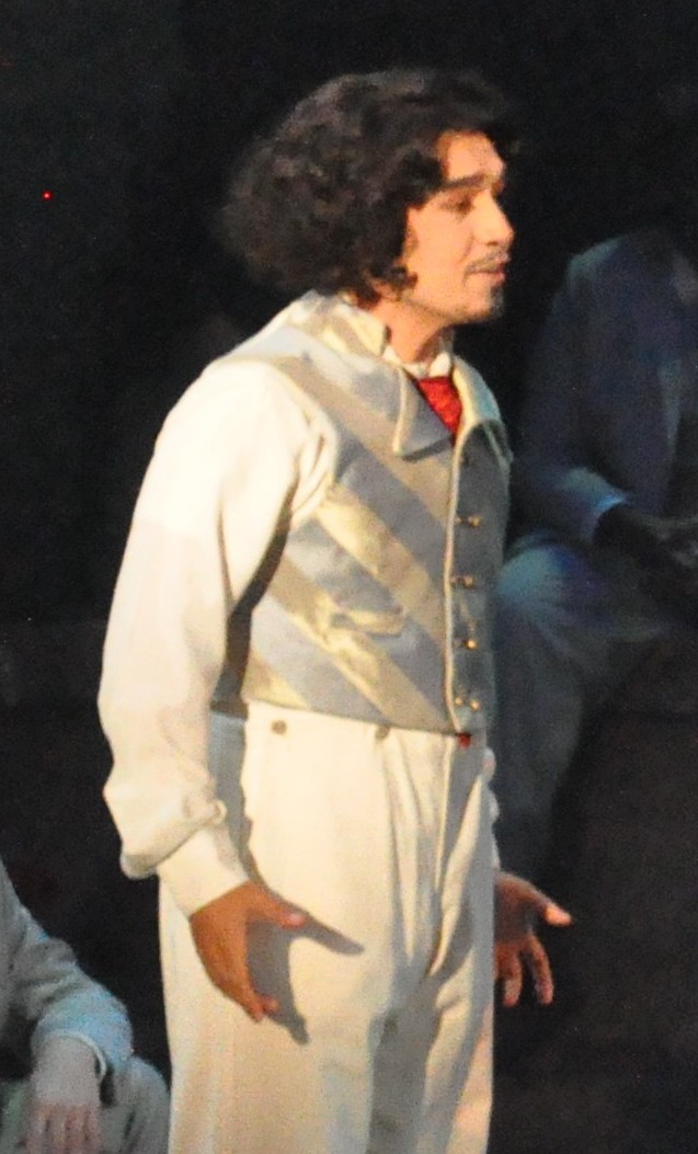 a man wearing a blue and gold striped vest, side view, light hits the shiny fabric so that the pattern matching is clear