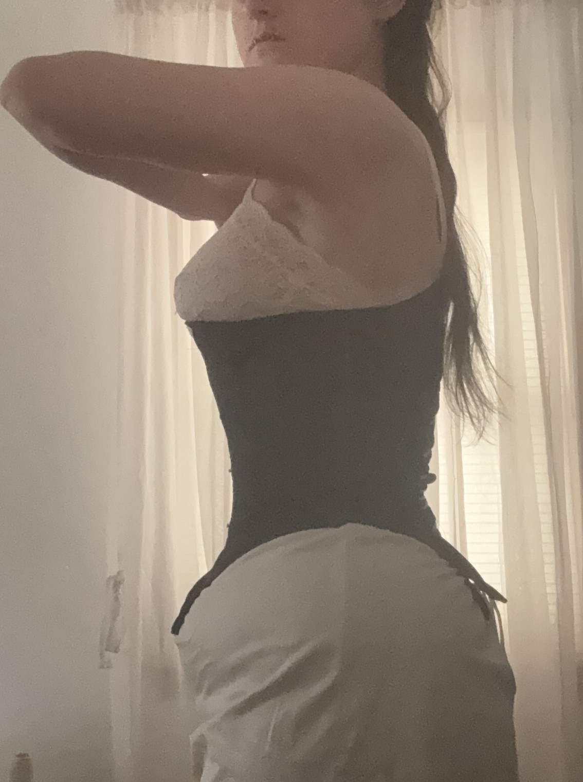 A black 1860's corset creating a flat, smooth transition from bust to waist to lower stomach, side view