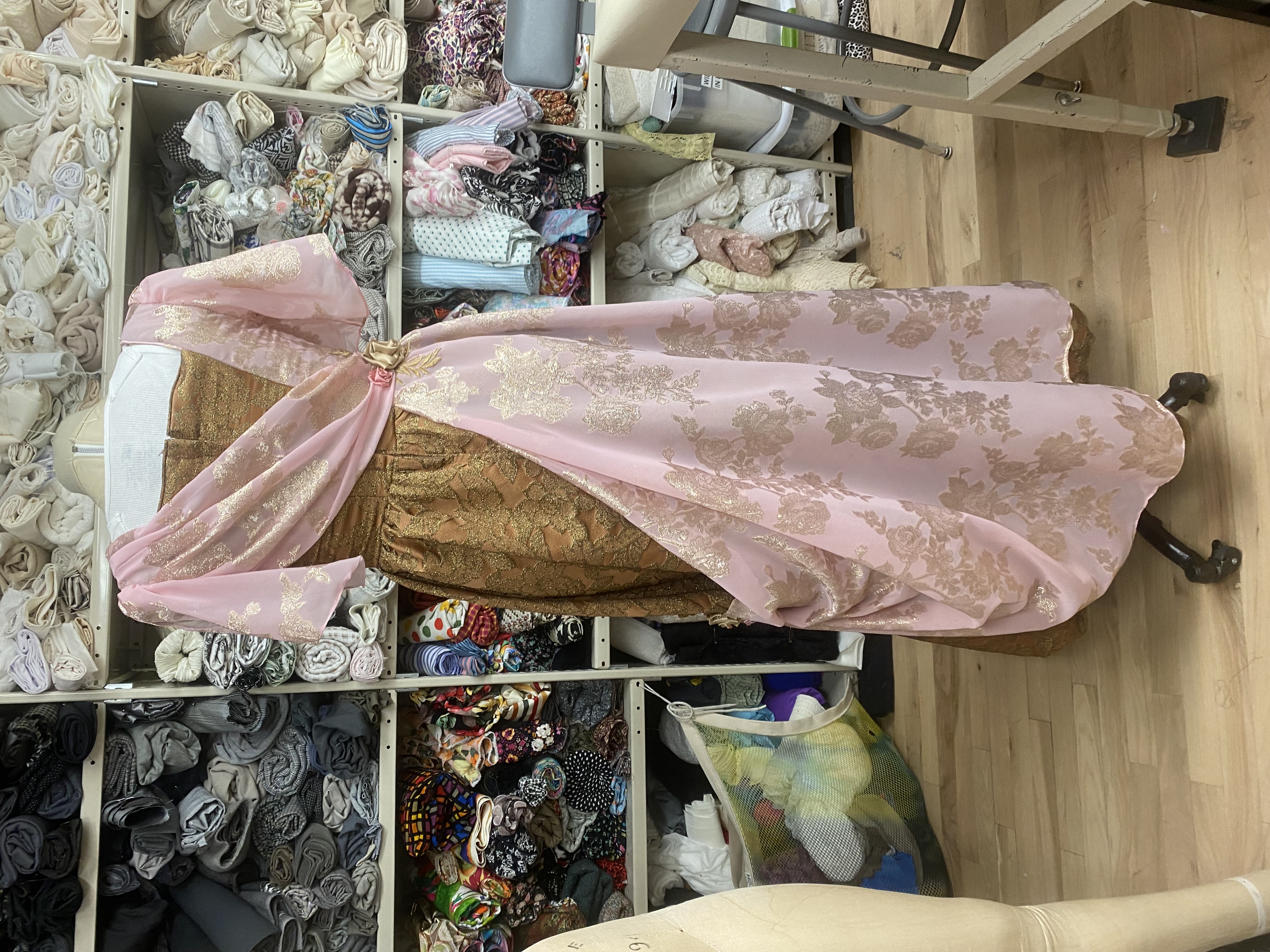 A woman in an edwardian bronze and pink gown, back view
