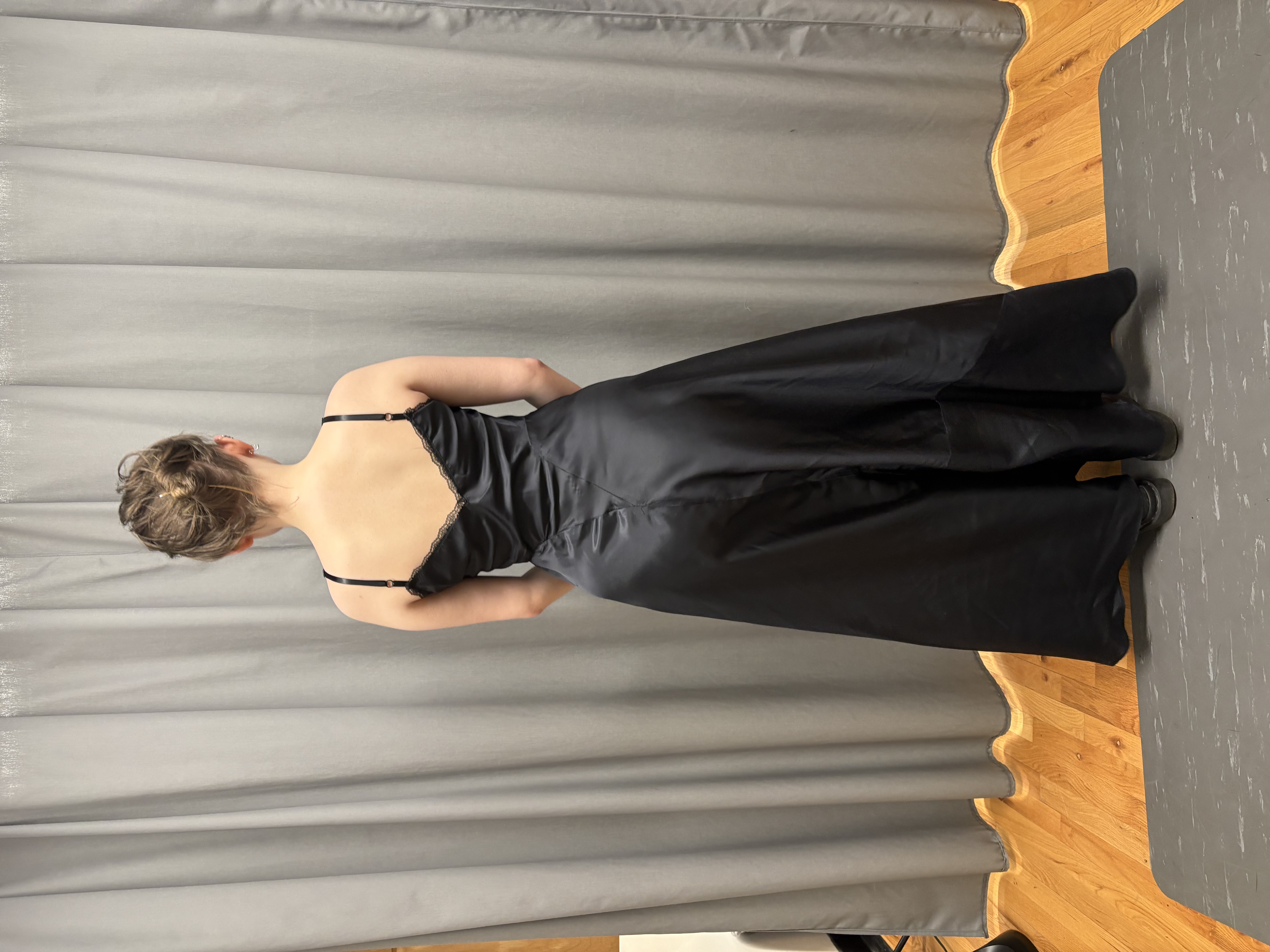 A woman in a long black slip facing back
