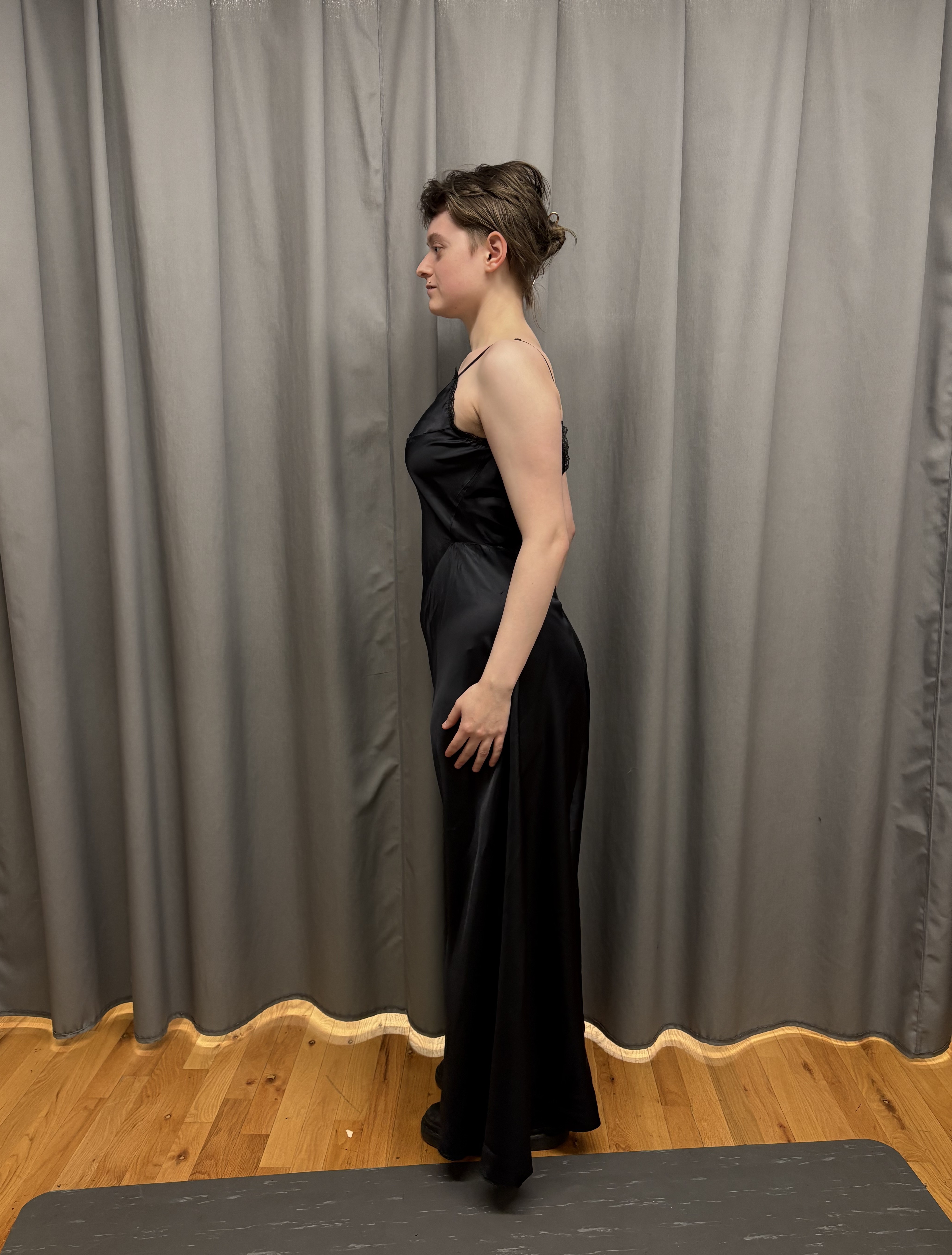 A woman in a long black slip facing to the side