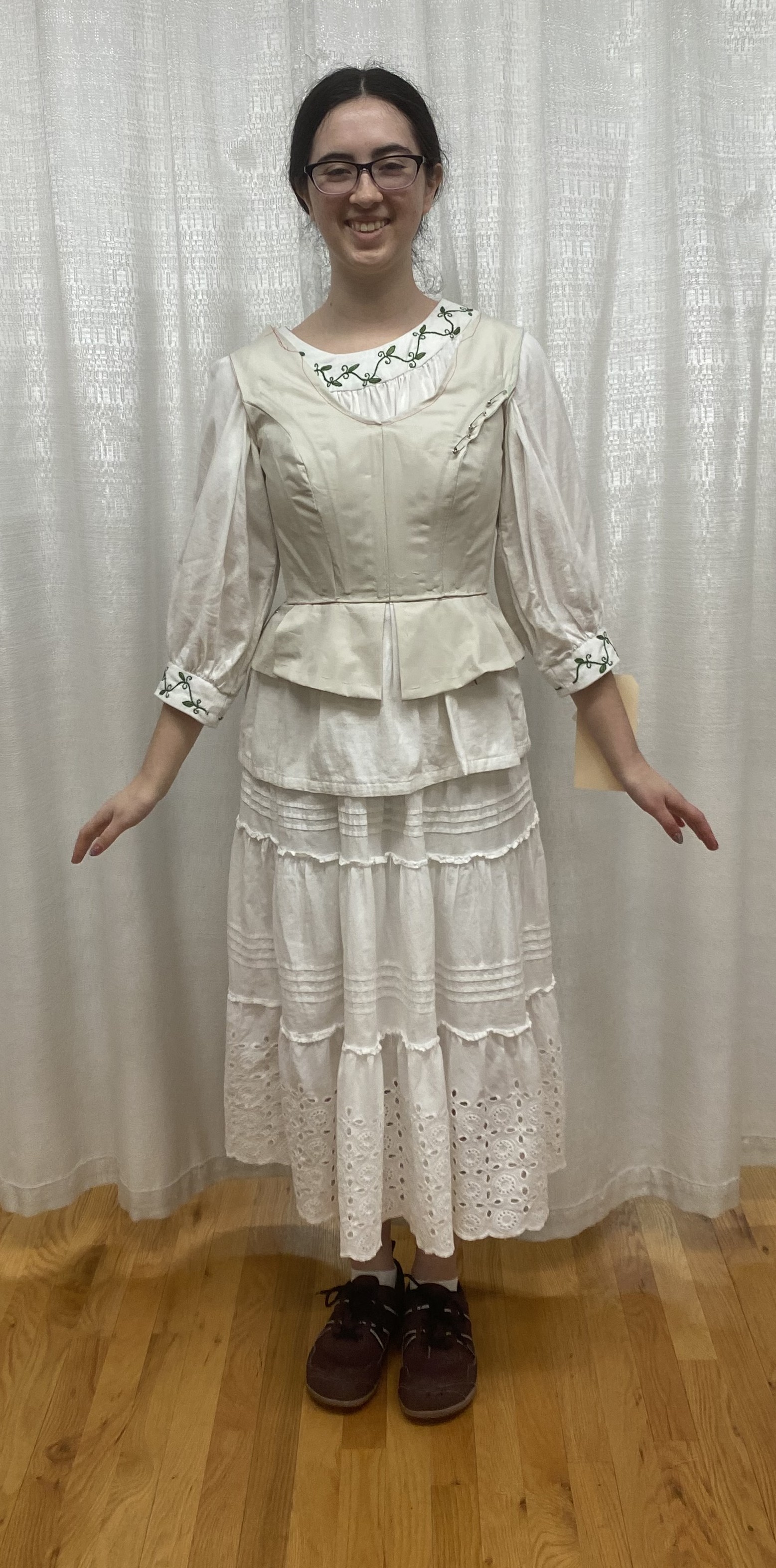 A woman in a long sleeve white shirt with a muslin bodice mock up on top, front view