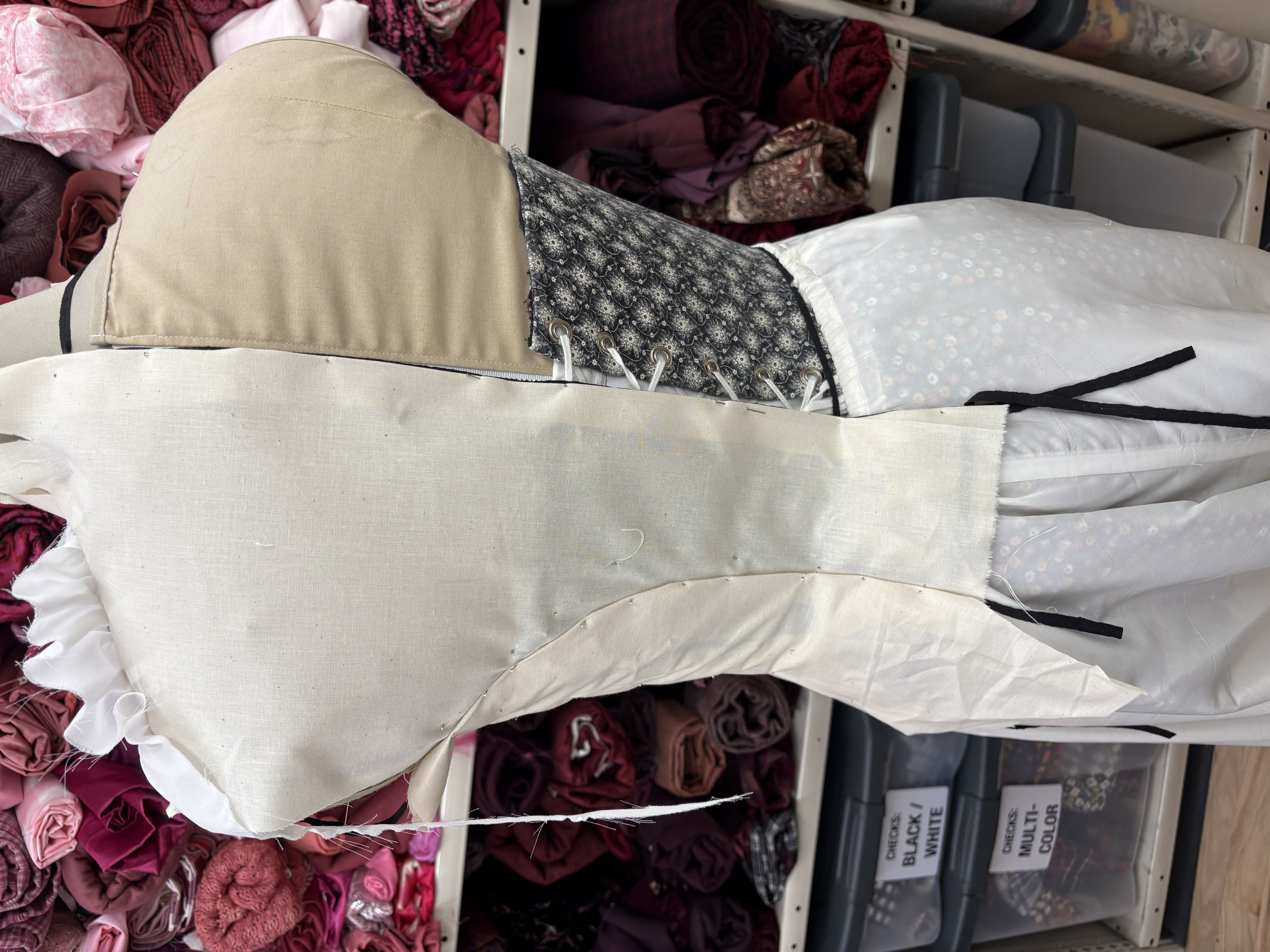 Pattern pieces marked on a dressform with muslin, back view
