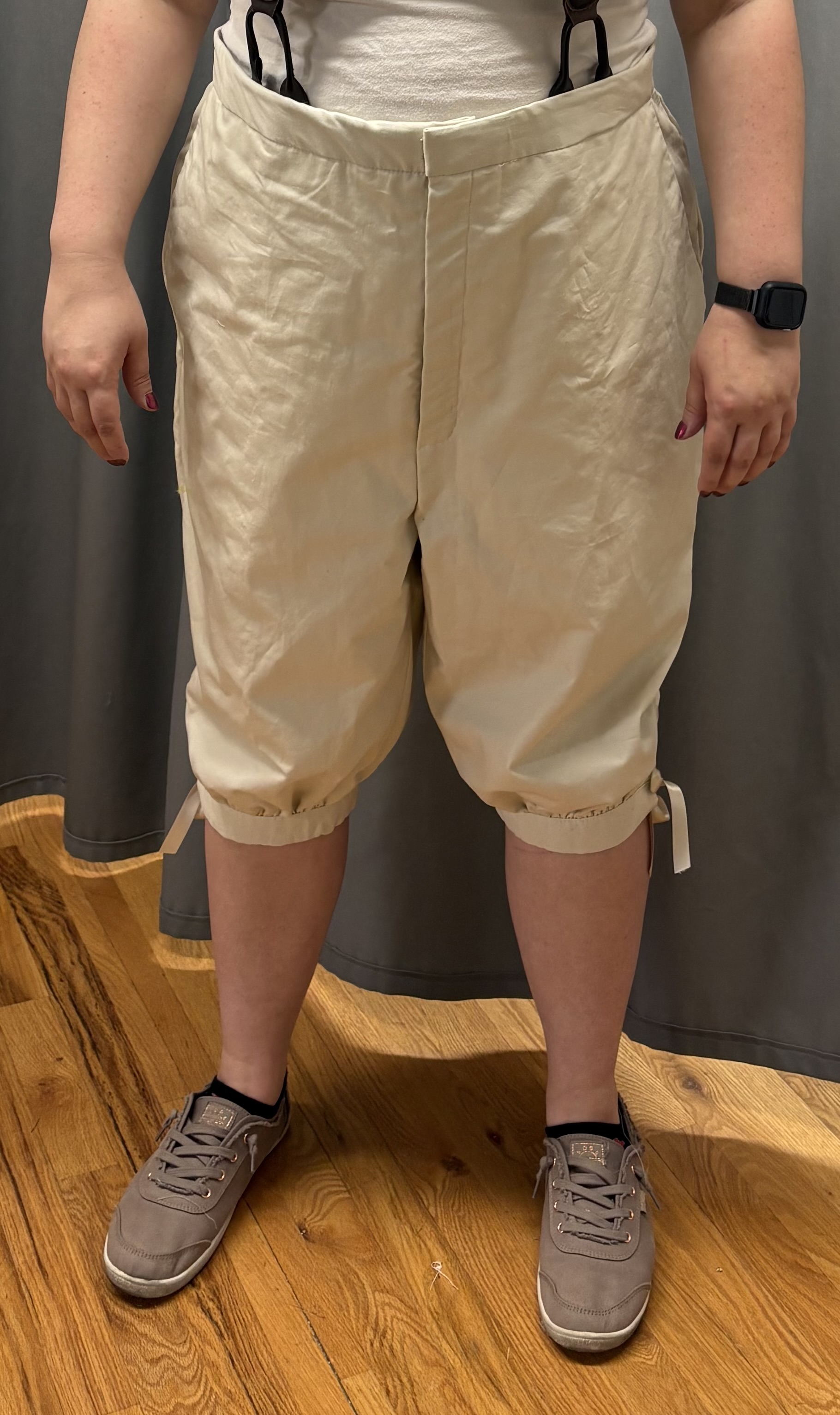 A woman in beige georgain breeches and suspenders, front view