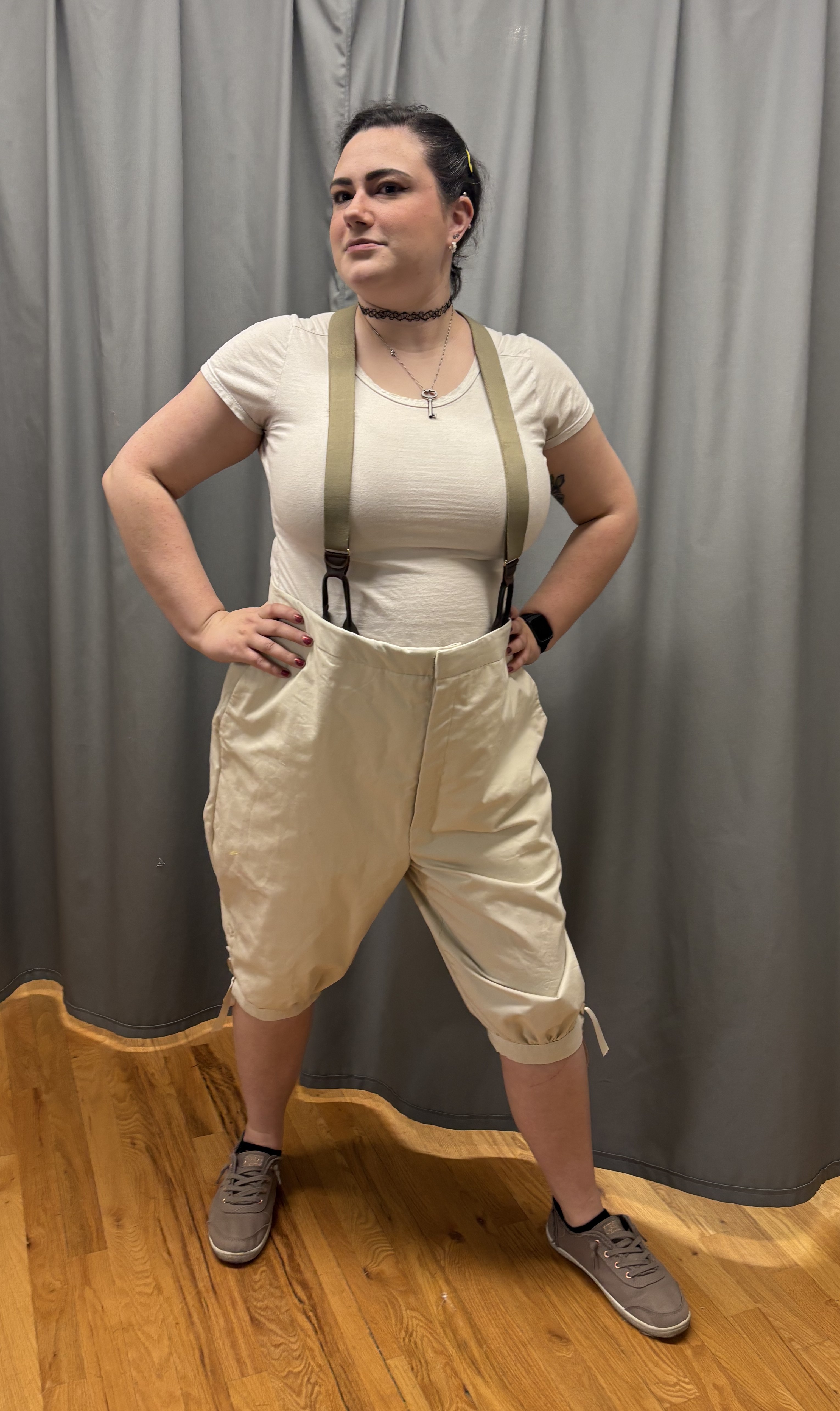 A woman in beige georgain breeches and suspenders, full length front view