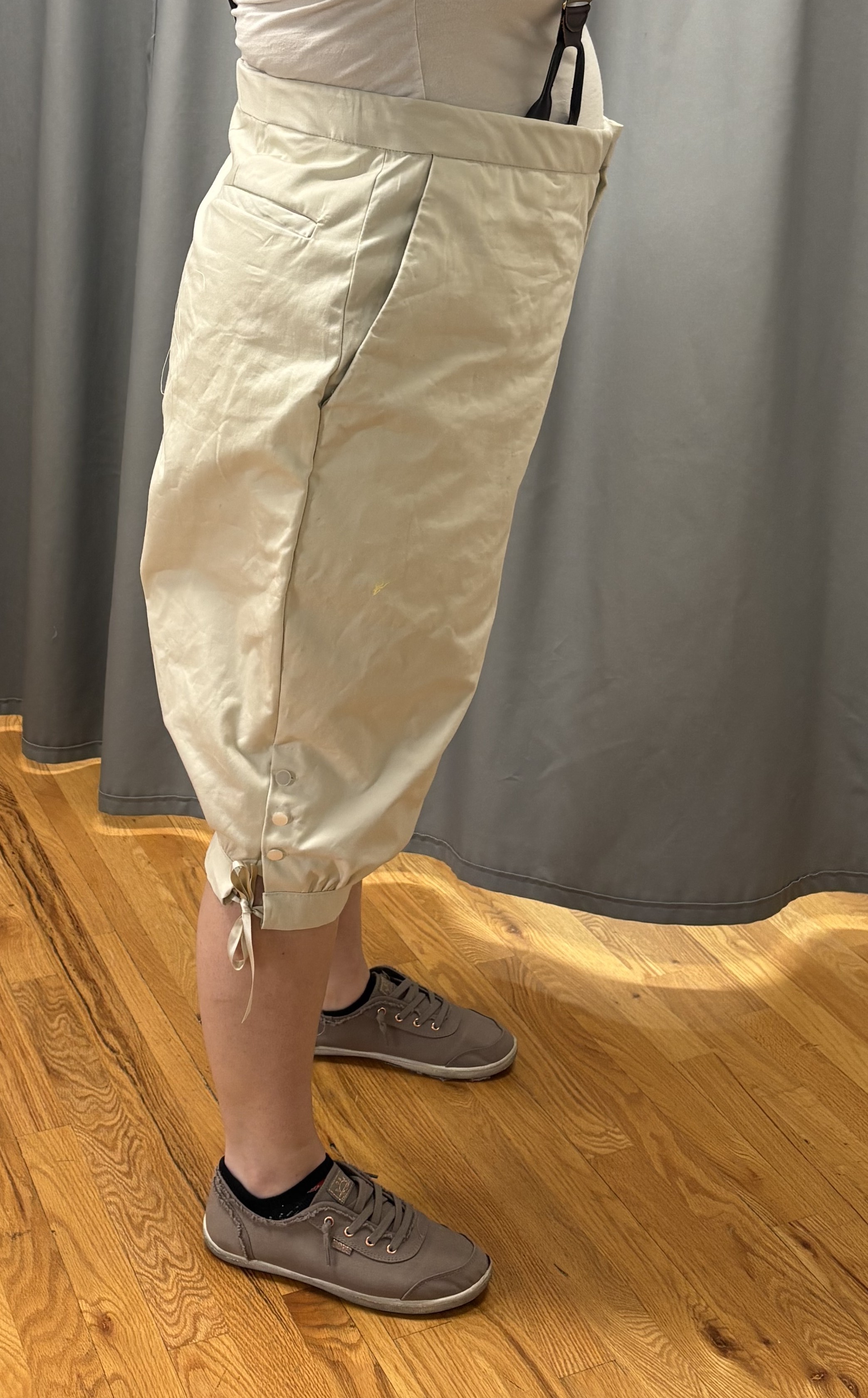 A woman in beige georgain breeches and suspenders, side view