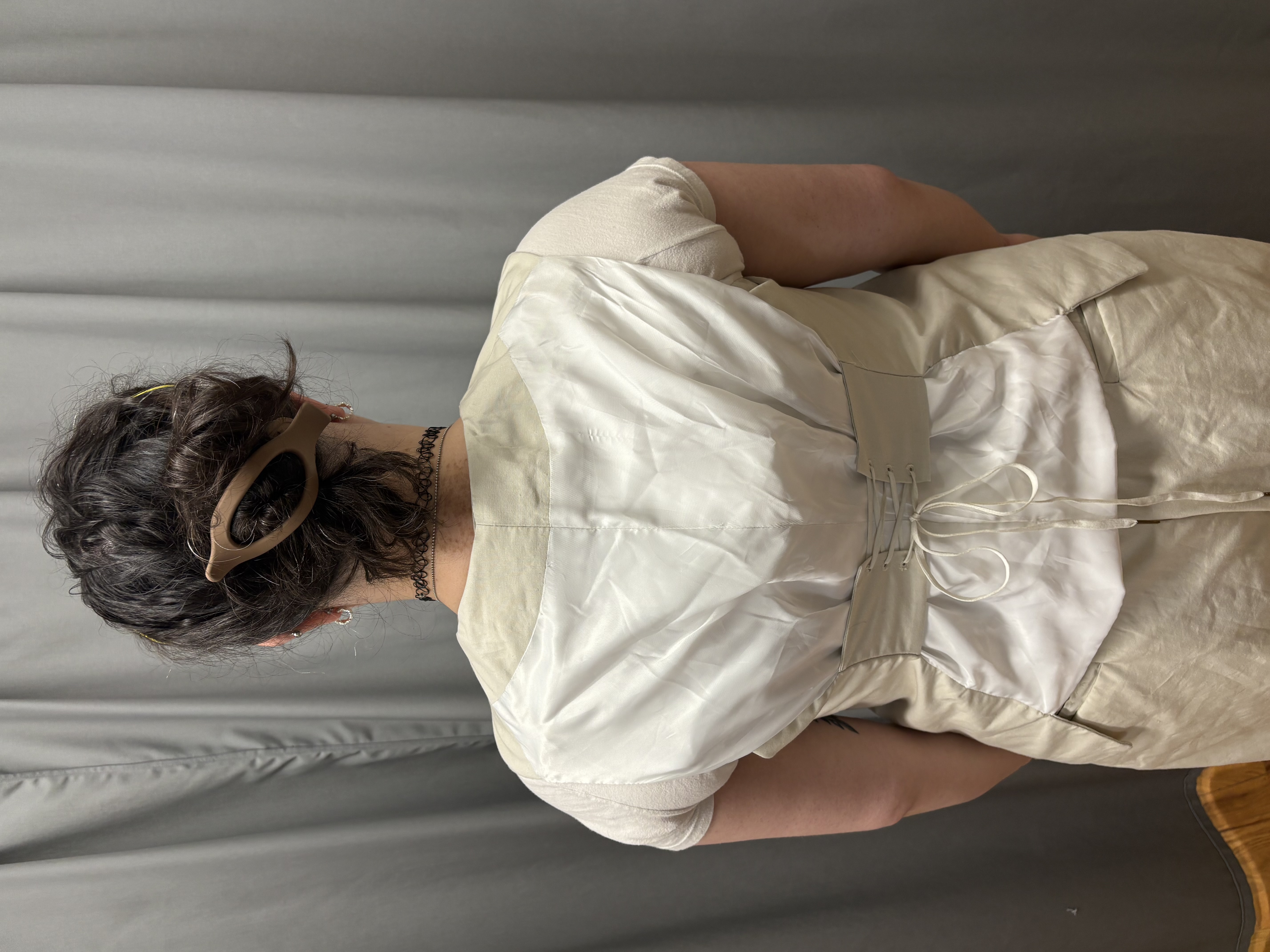 A woman in a beige georgian vests, vest back view