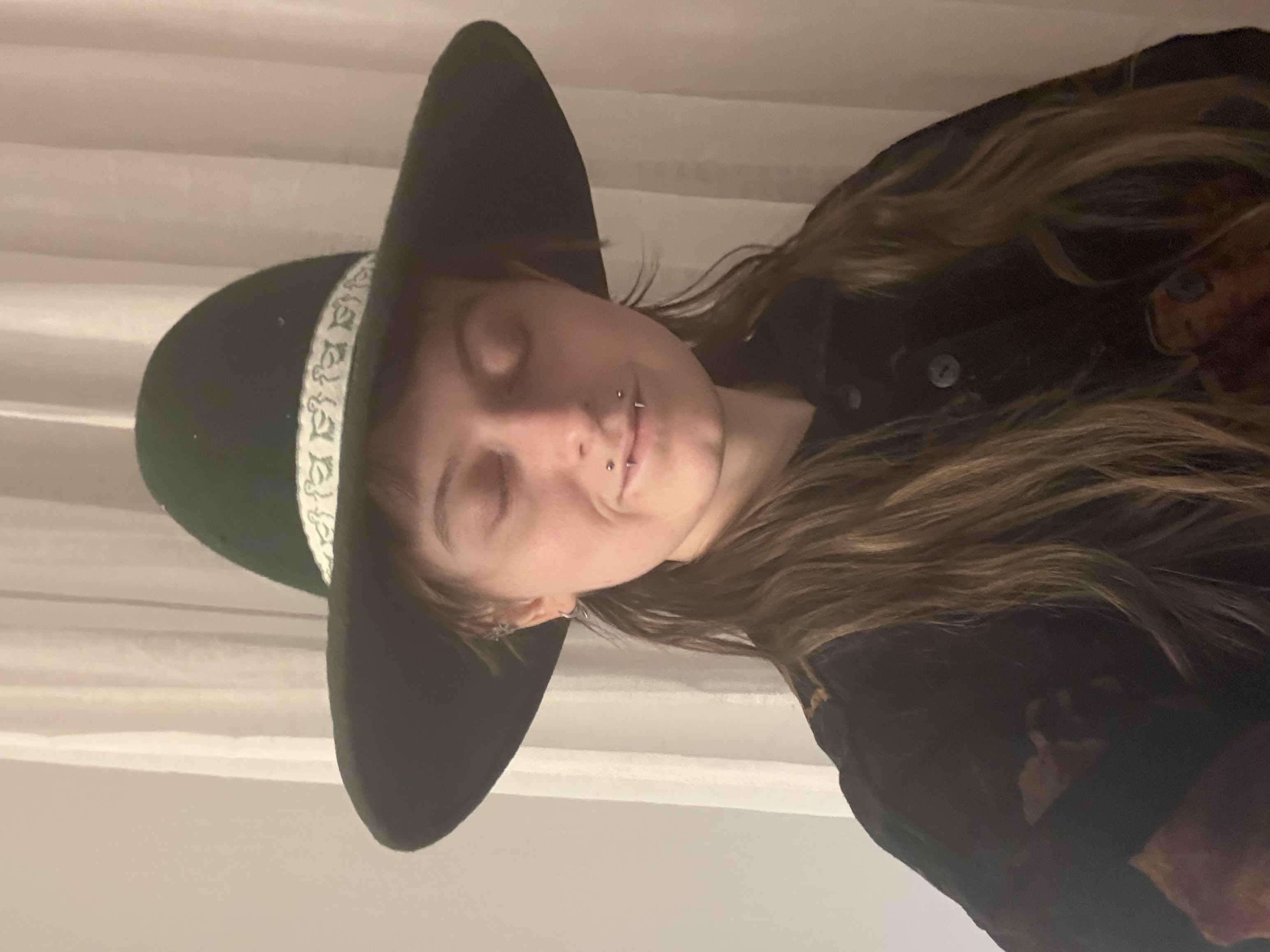A green wide brimmed hat with a white hatband, front veiw of underbrim
