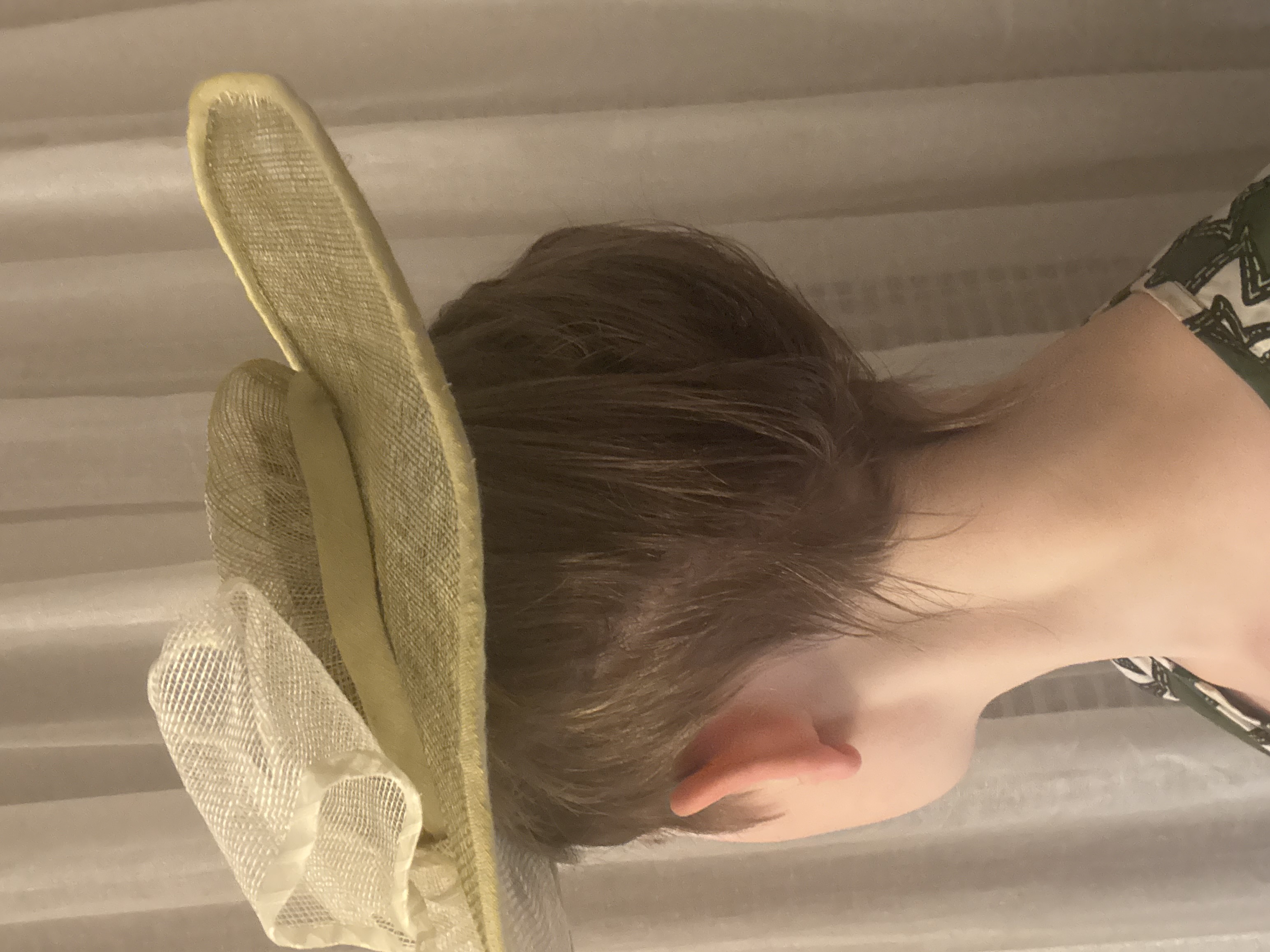 A light green widebrimmed round hat with big white bow, back view