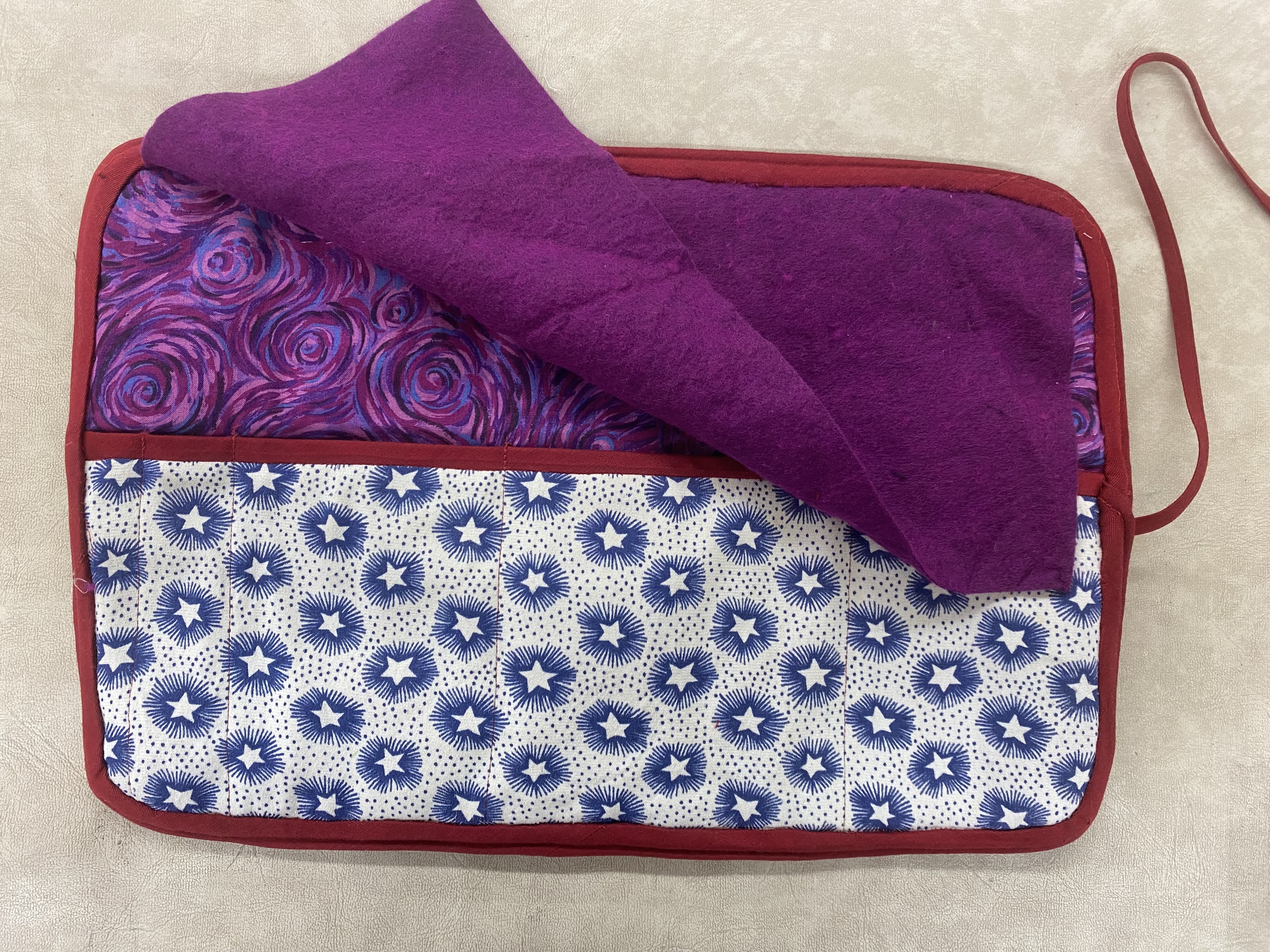 the back of the quilt, a large pocket going across the back. the pocket is white with blue stars and the fabric behind it is purple swirls